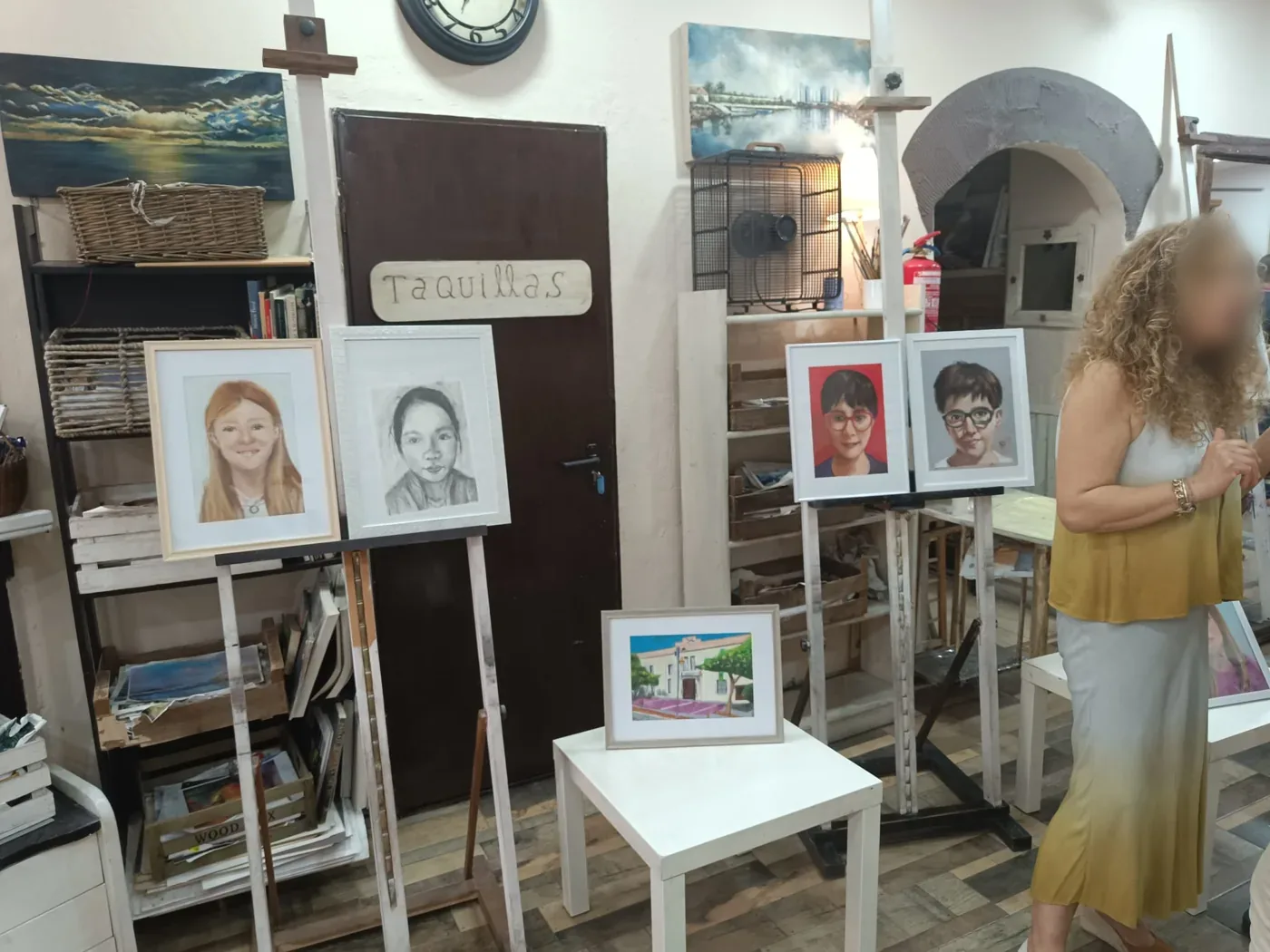 Retratos dibujados expuestos en caballetes en el taller